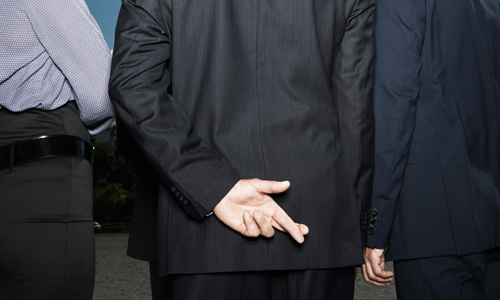 3 men standing with their backs to us with one man crossing his fingers behind his back