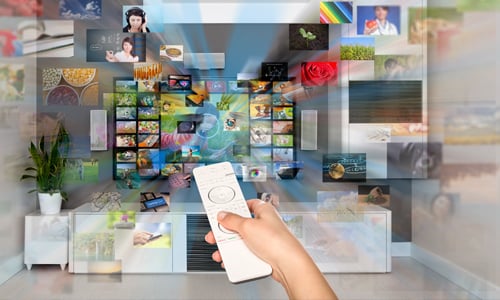 Person holding remote control towards TV with various channels popping out