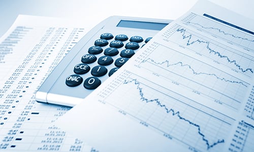 Close-up of a calculator, reports with line charts and data